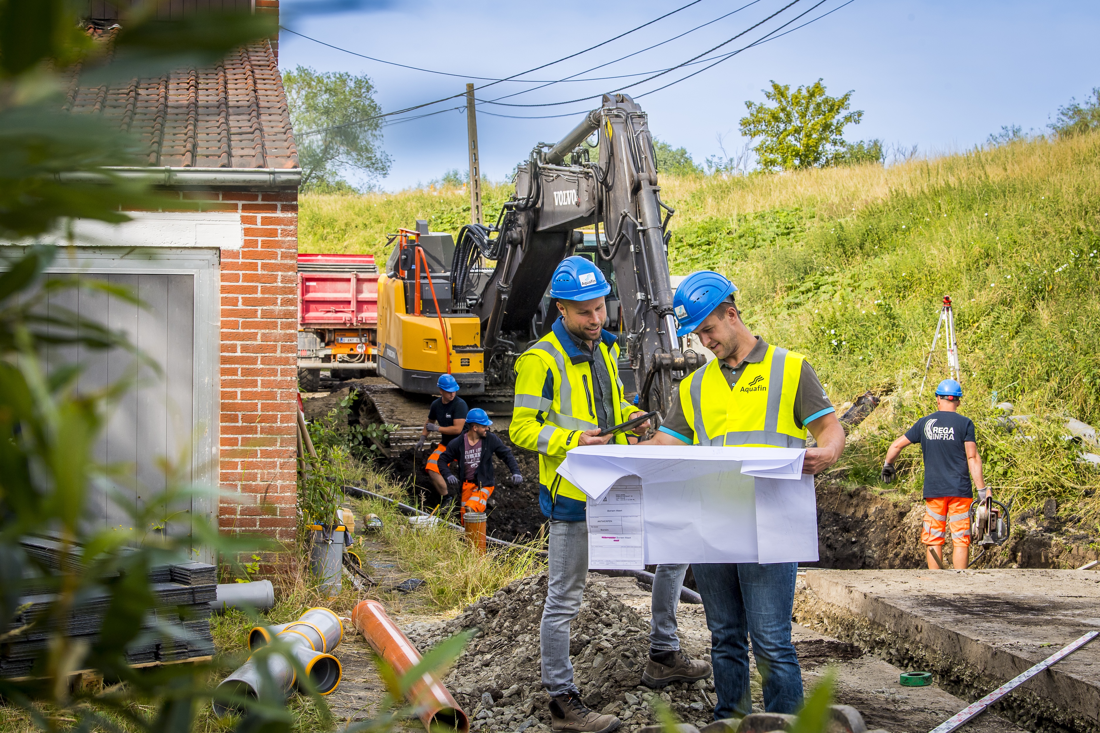 Aquafin medewerkers op een rioleringswerk werf met graafmachines