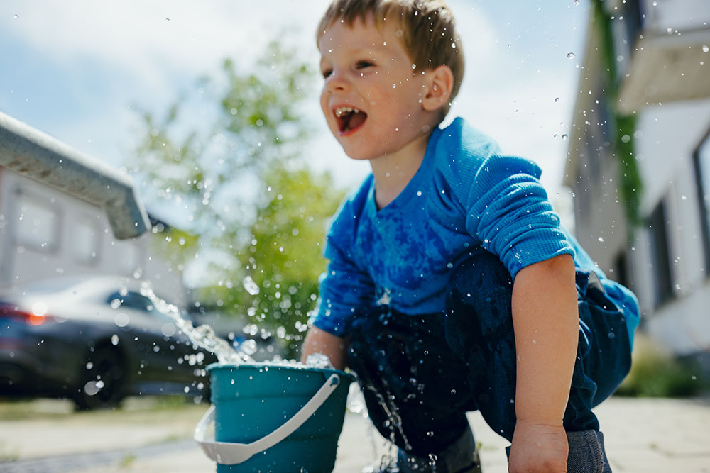kind spelend met water in de stad
